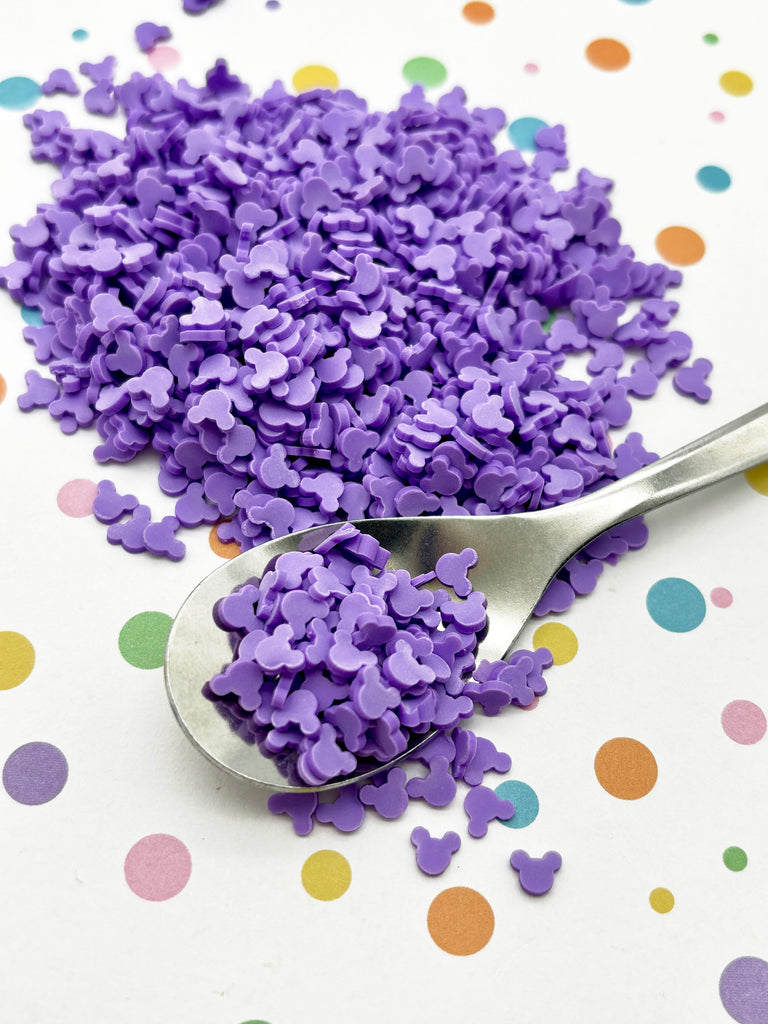 a spoon filled with purple confetti on top of a table