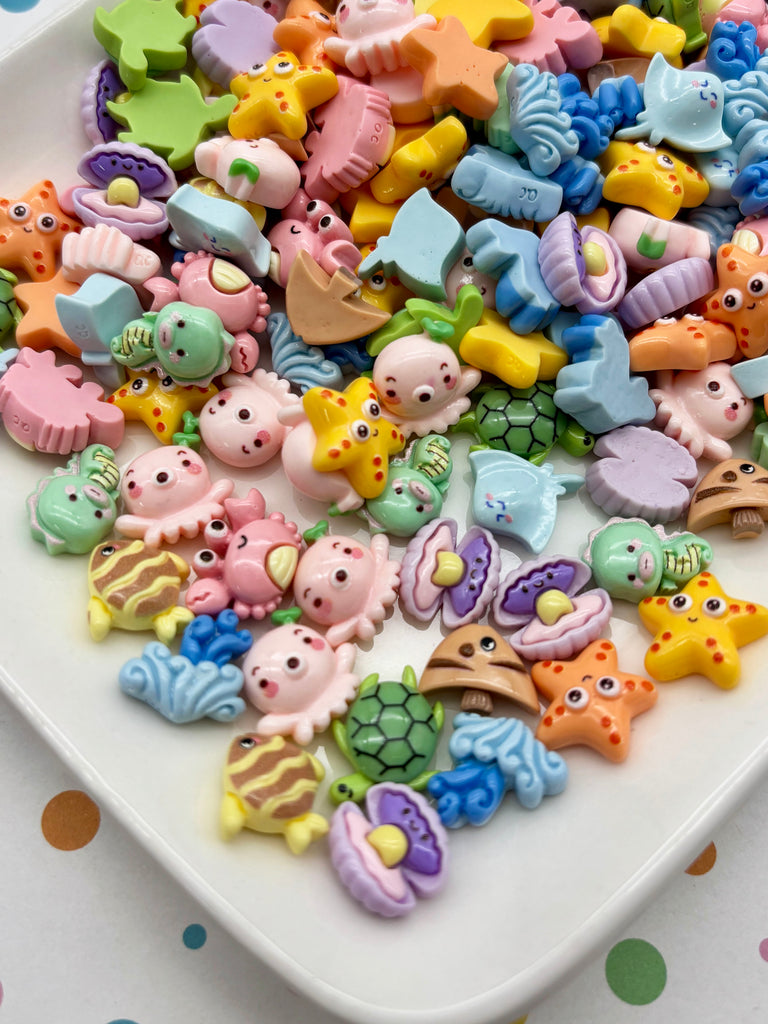 A white plate filled with a variety of colorful, whimsical toy animal figurines, including starfish, octopuses, and other sea creatures.