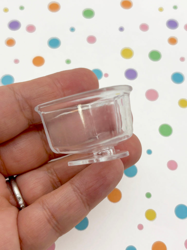 A hand is holding a clear plastic cup with a colorful polka dot background.
