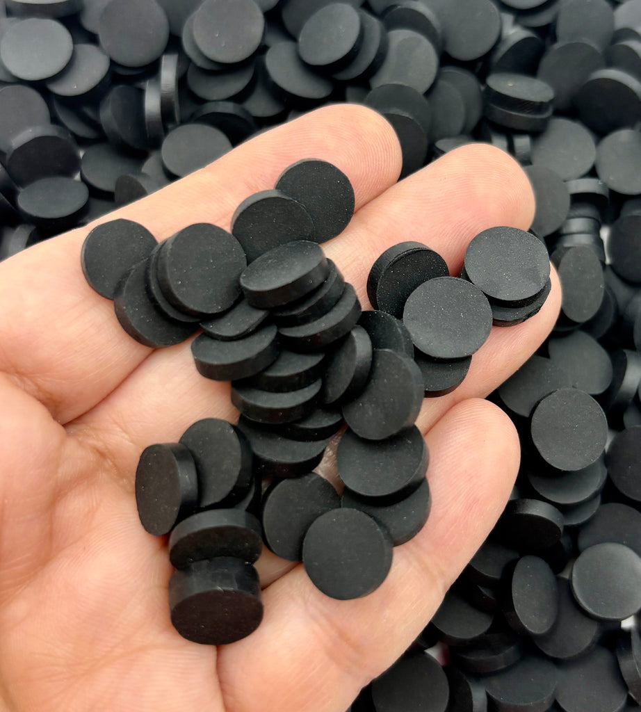 a hand holding a pile of black plastic discs