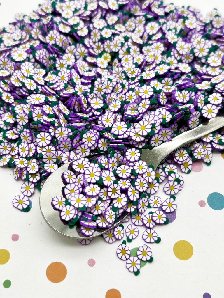 a pile of purple and white flowers next to a spoon