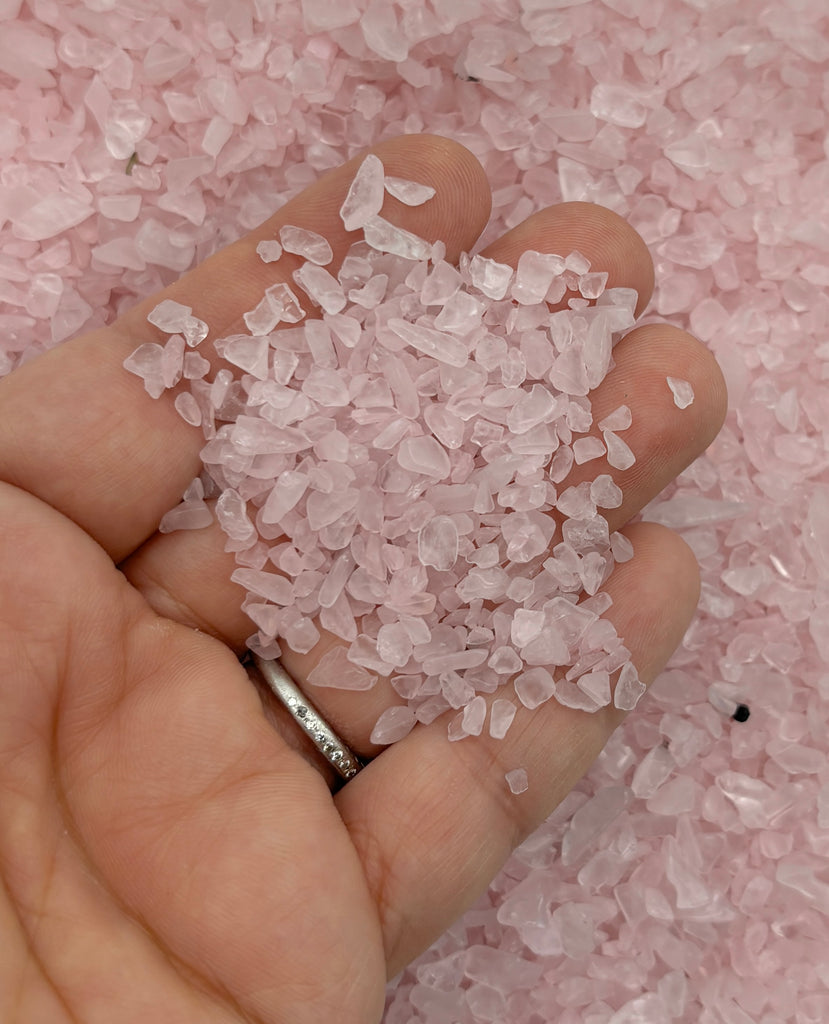 a person holding a handful of pink crushed sugar