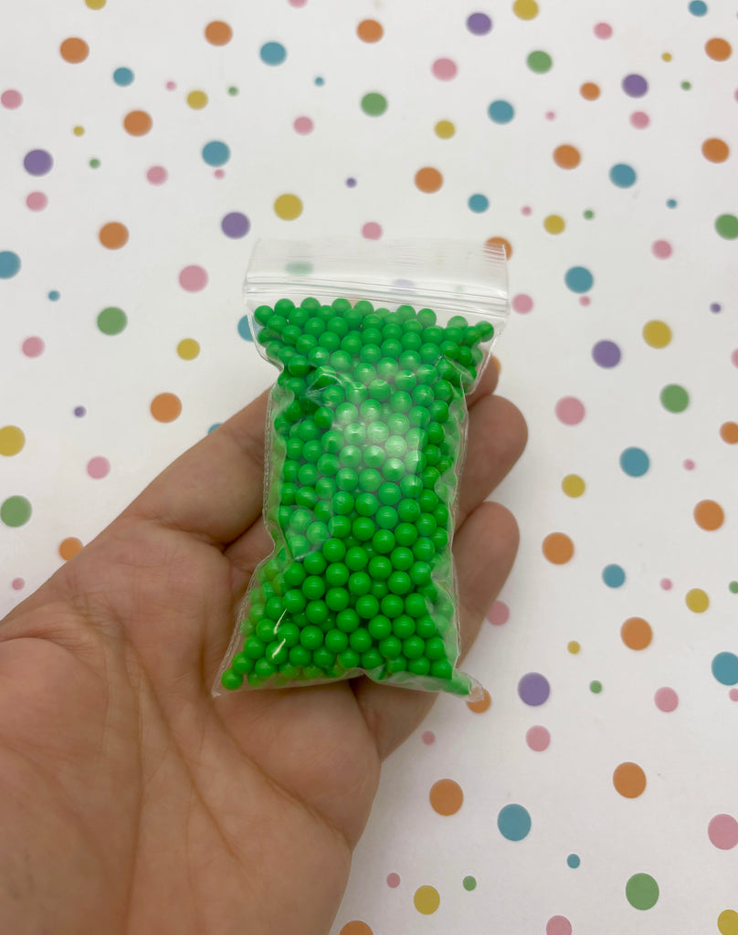 a hand holding a bag of green beads