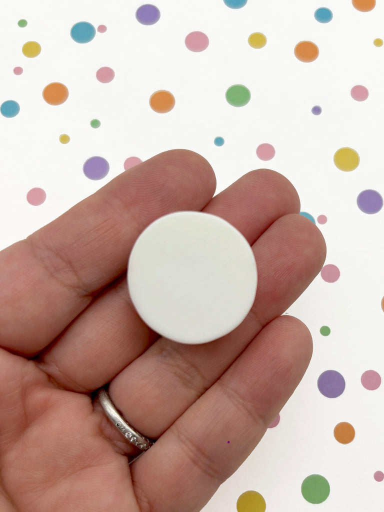 A hand holding a white object against a background of colorful polka dots.