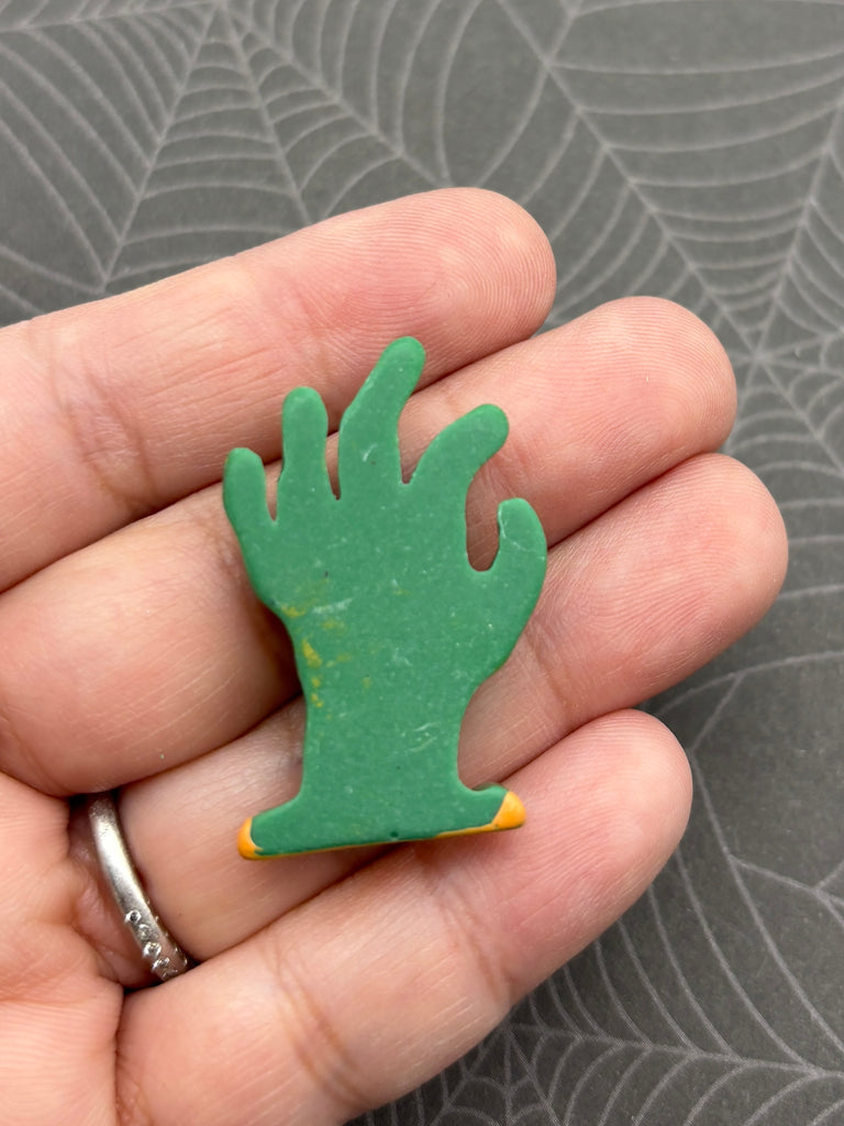 A hand holding a green, hand-shaped object against a gray background.