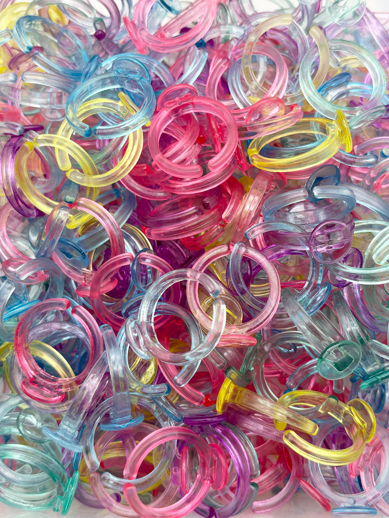 The image is a colorful pile of various plastic rings in different colors, including pink, blue, yellow, and green.