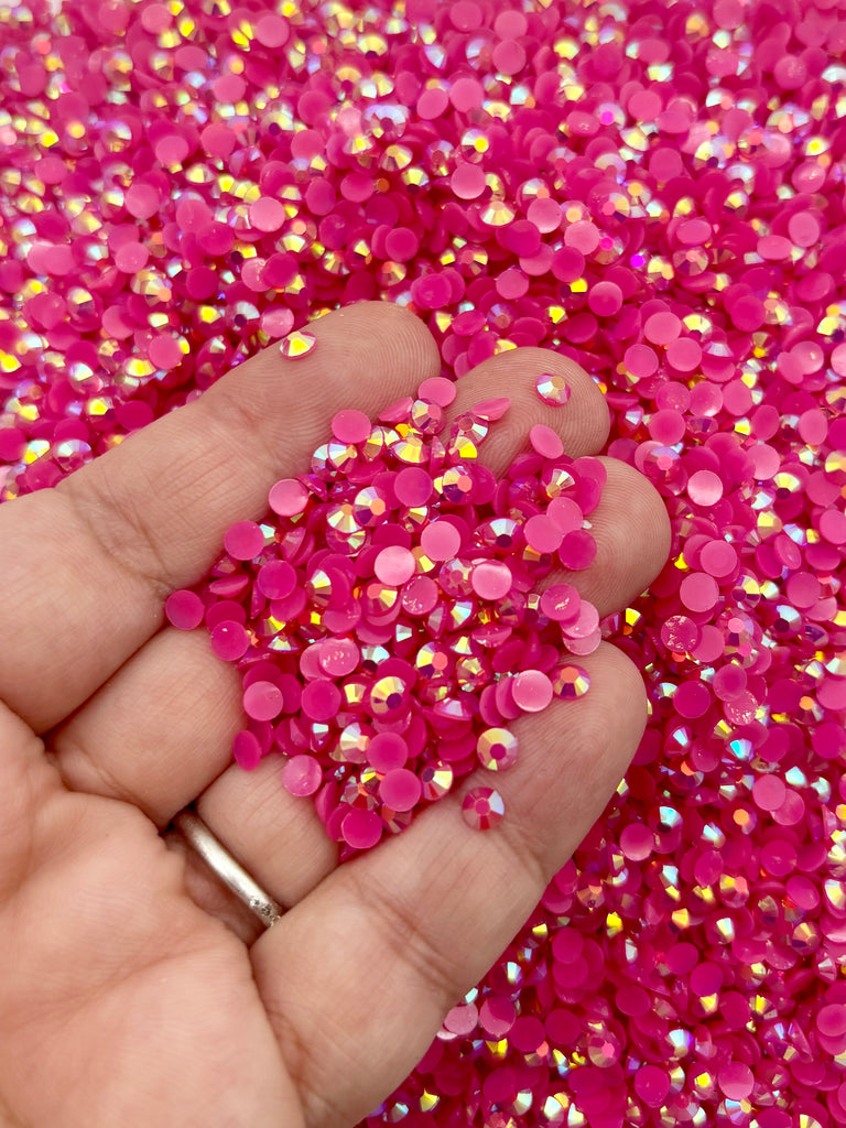 A hand holding a pile of pink and yellow glitter beads.