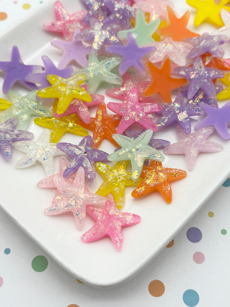 A white plate filled with a variety of colorful star-shaped objects, including glittery and multicolored star-shaped candies or decorations.