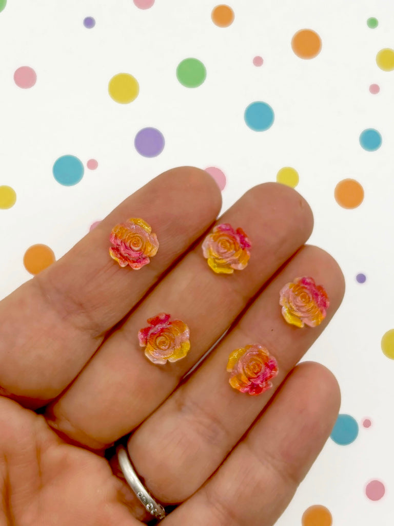 a hand holding a yellow and pink rose on it's fingers