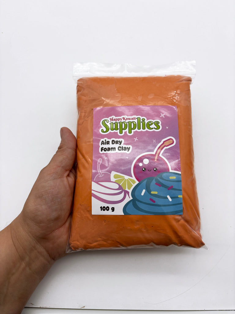 A hand holding a bag of orange-colored foam clay with a label that includes a cartoon character and text.