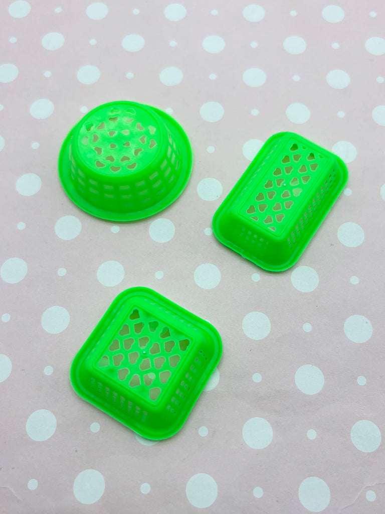 three green plastic baskets with holes on a white polka dot background.