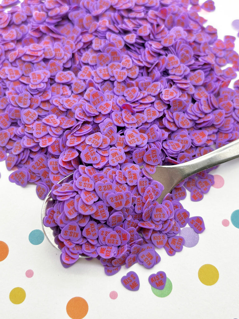 a spoon full of purple buttons sitting on top of a table