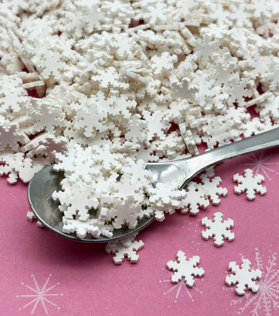 a spoon full of snow flakes on a pink surface