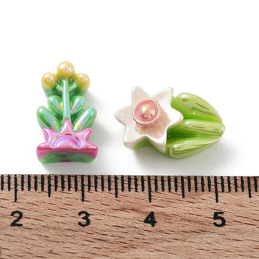 two colorful ceramic flower-shaped objects placed next to a ruler for size comparison.