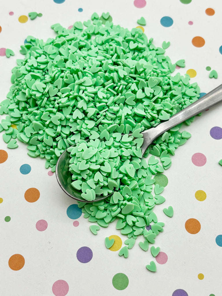 a spoon filled with green sprinkles on top of a table