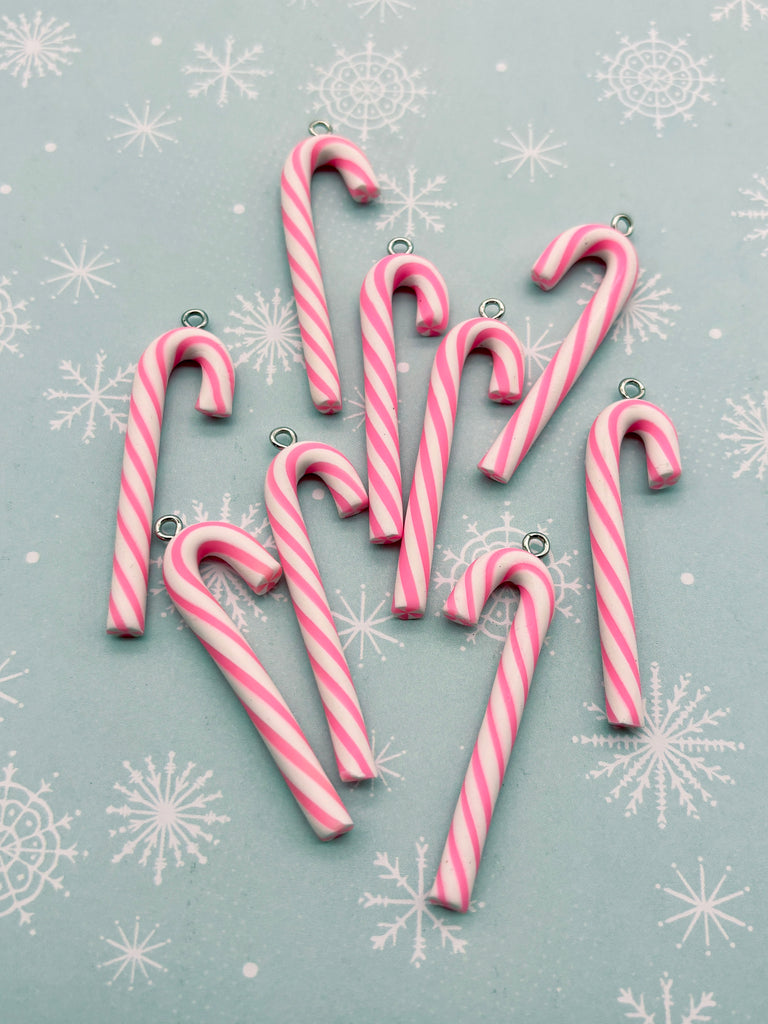 a collection of pink and white striped candy canes arranged on a light blue background with white snowflakes.