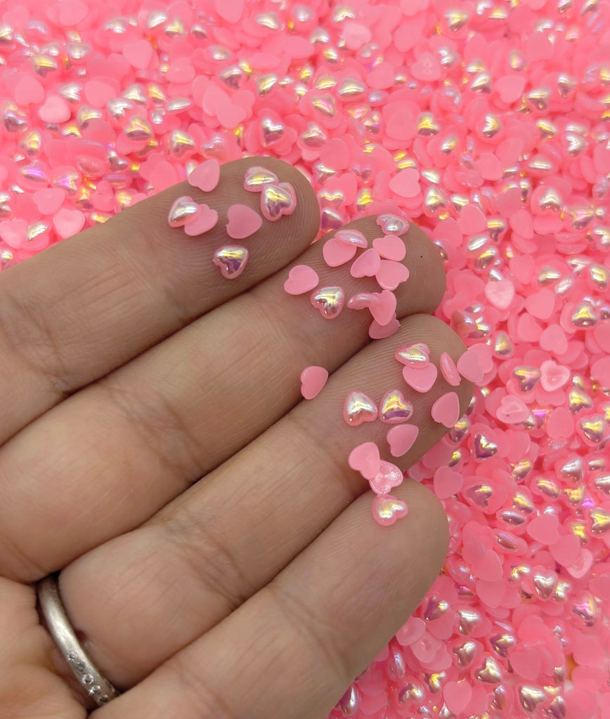 a hand holding a pink manicure with hearts on it