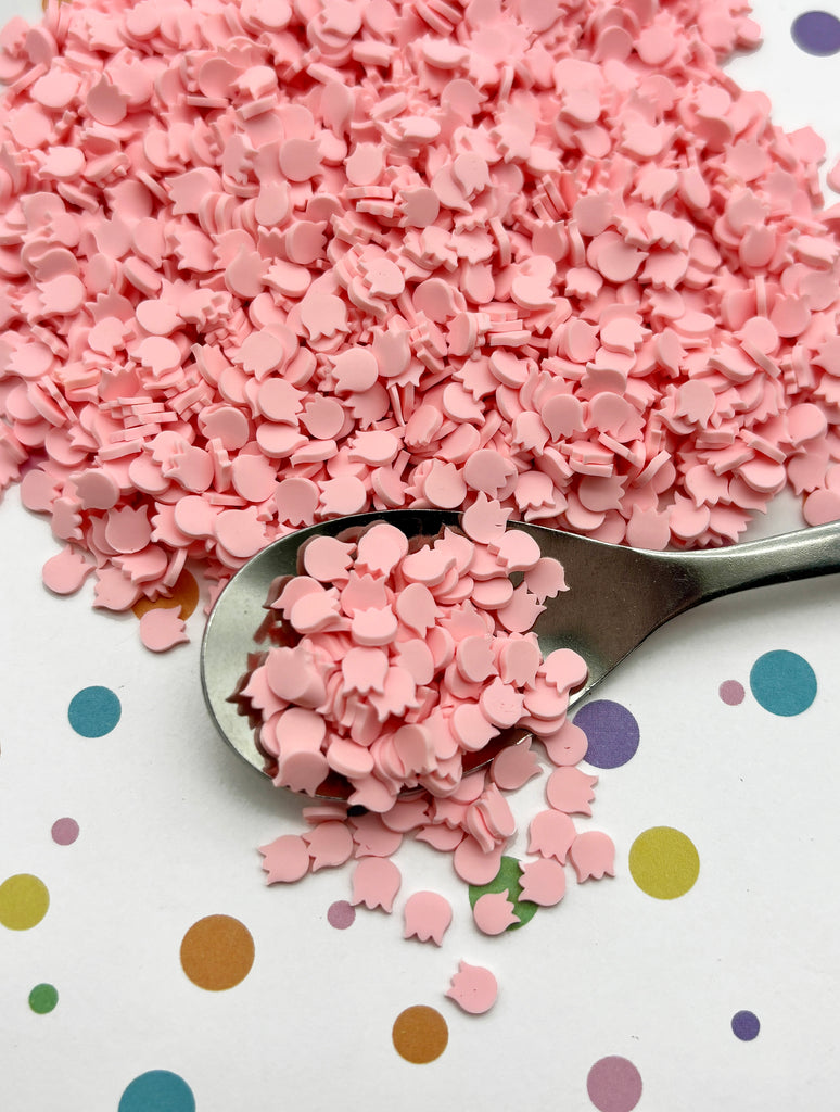 a spoon full of pink sprinkles on a table