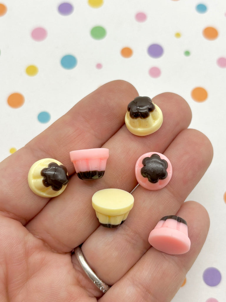 A hand holding a collection of colorful, small candy pieces against a background with polka dots.