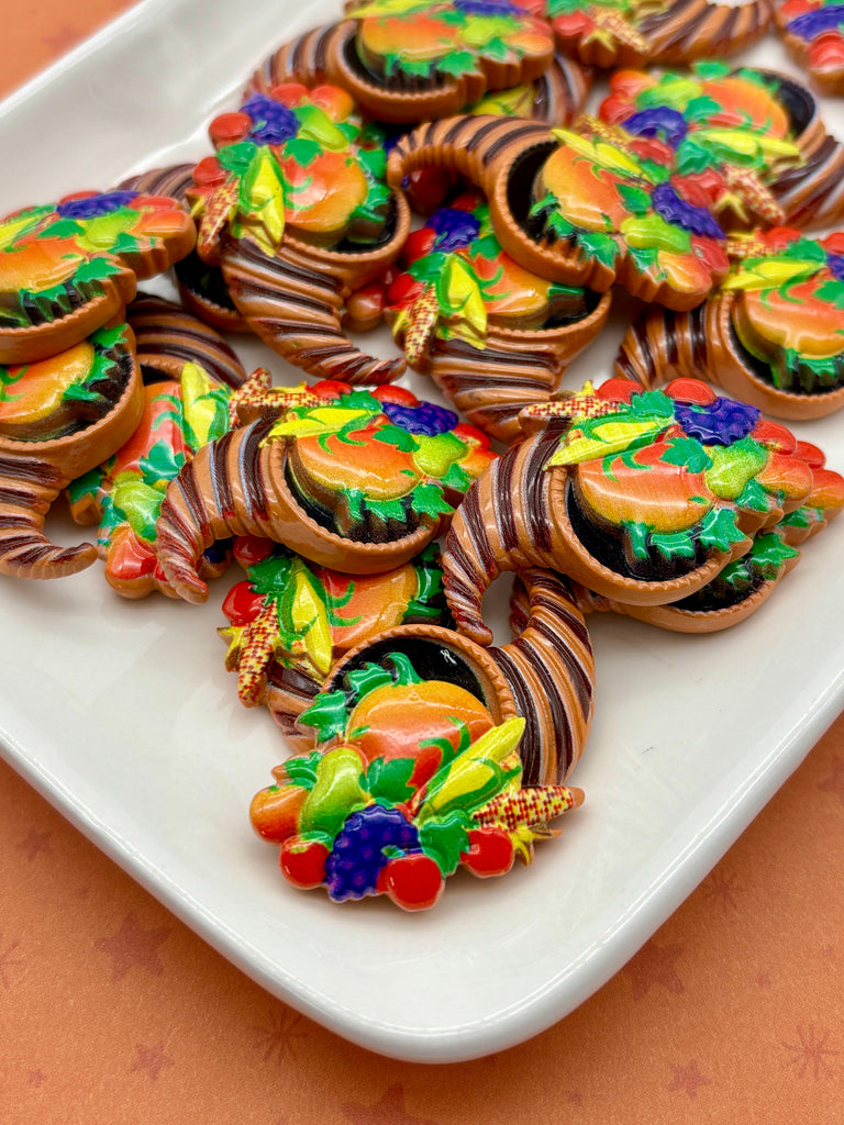 a white plate filled with colorful, decorative cookies or pastries, featuring various fruits and vegetables as toppings.