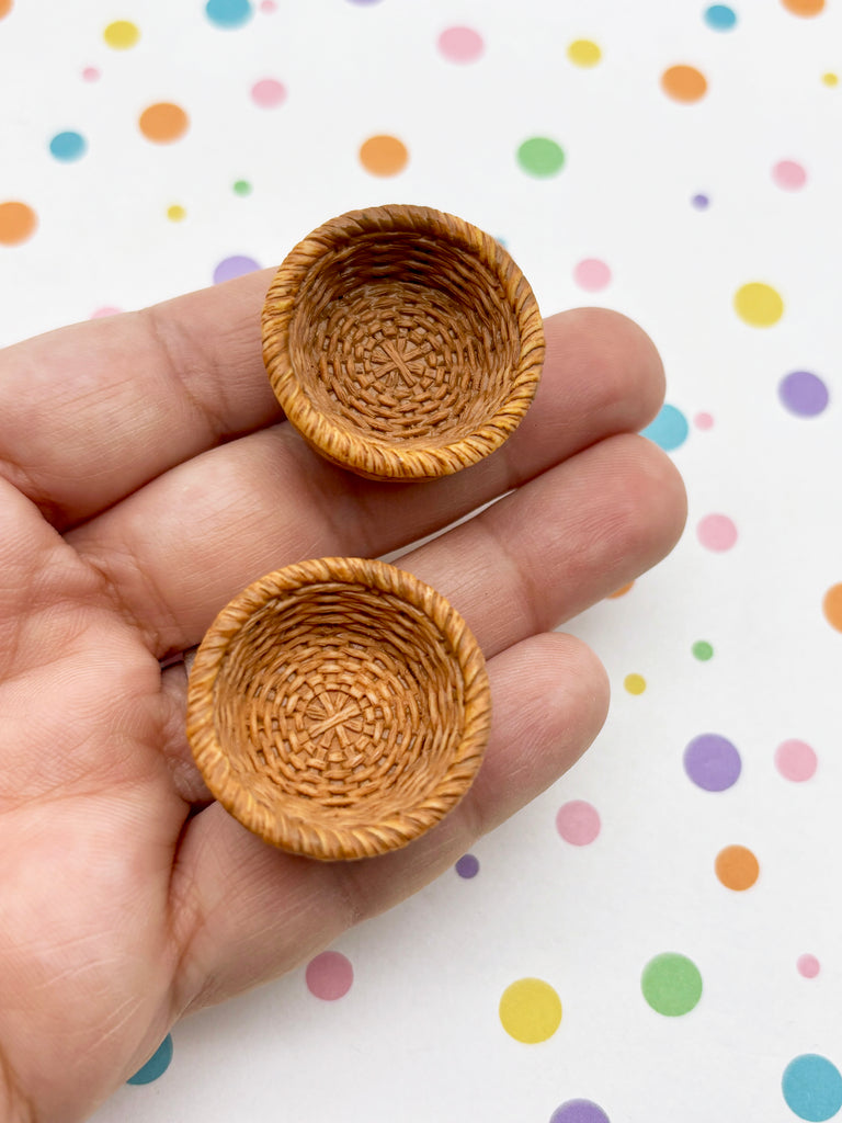 A hand holding two small, round woven baskets against a background with colorful polka dots.