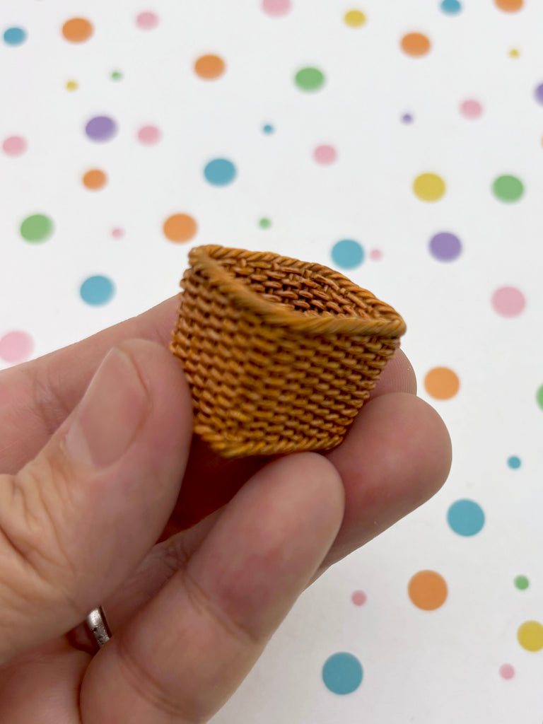 A hand is holding a small woven basket against a background with colorful polka dots.