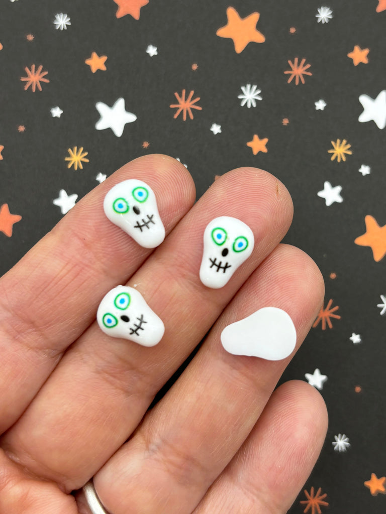 a hand holding a white manicure with a skull on it