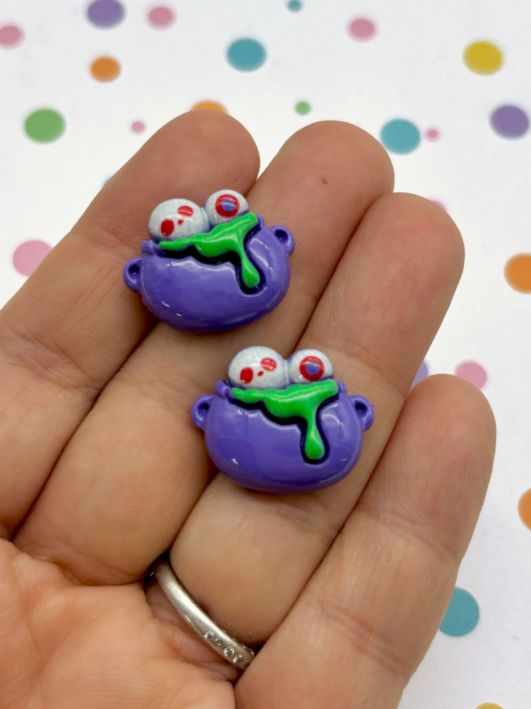 a hand holding two small purple and green items