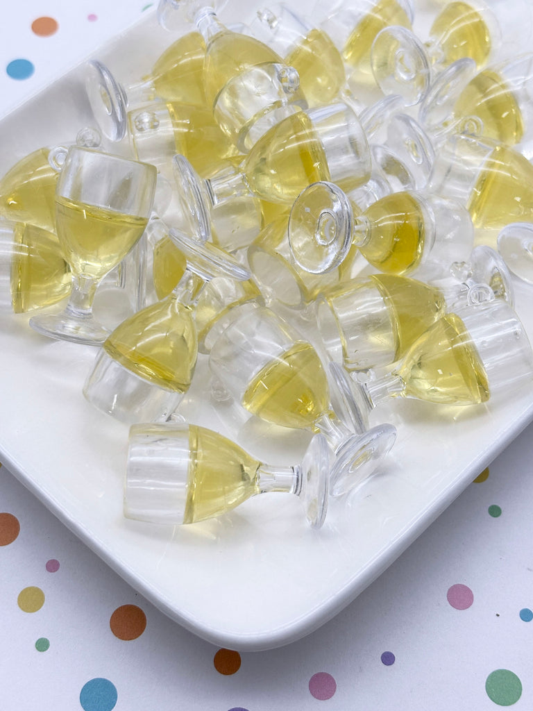 a white plate filled with numerous small, clear plastic cups or glasses containing a yellow liquid, possibly a beverage. The cups are arranged in a scattered pattern on the plate, creating a visually interesting and playful display.