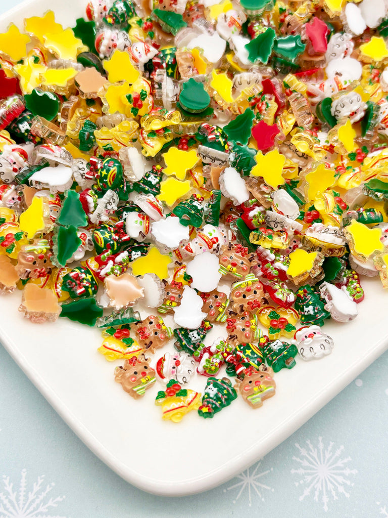 A white plate filled with a variety of colorful, festive-themed candies, including Christmas-themed candies and other decorative elements.