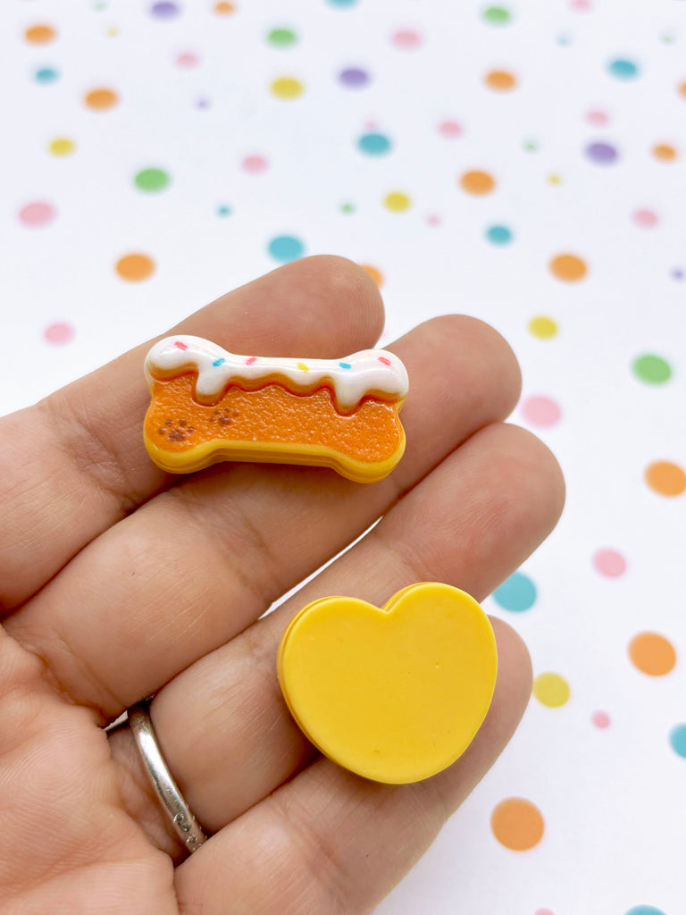 a hand holding a small yellow and white doughnut