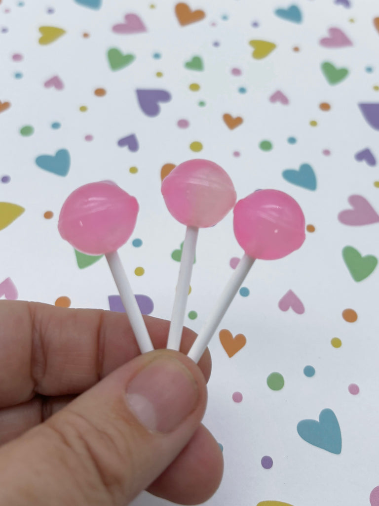 a hand is holding two lollipops on a stick