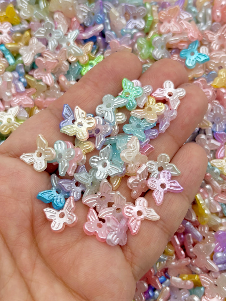 A hand holding a collection of multicolored, small beads in various pastel shades, including shades of pink, blue, green, and yellow.