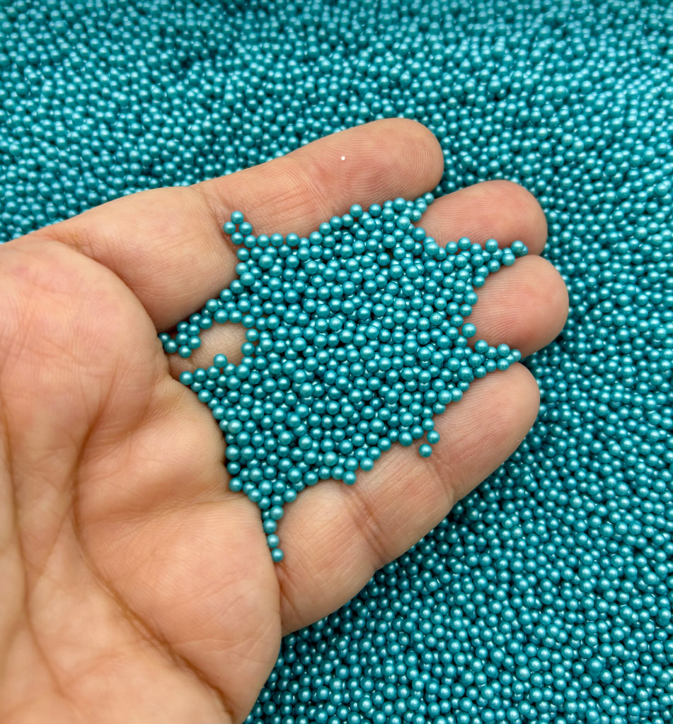 a hand holding a handful of blue beads