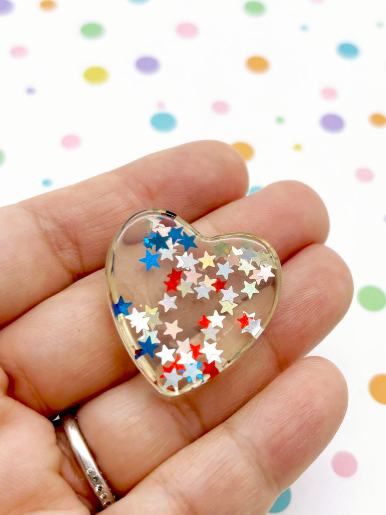 a person holding a heart shaped brooch in their hand