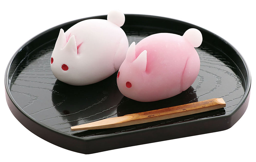 a couple of pink and white animals sitting on top of a black plate