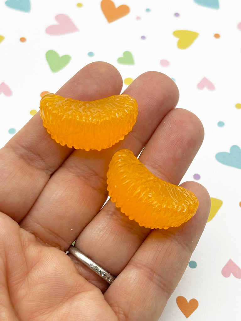 a hand holding a pair of tiny orange gummy bears