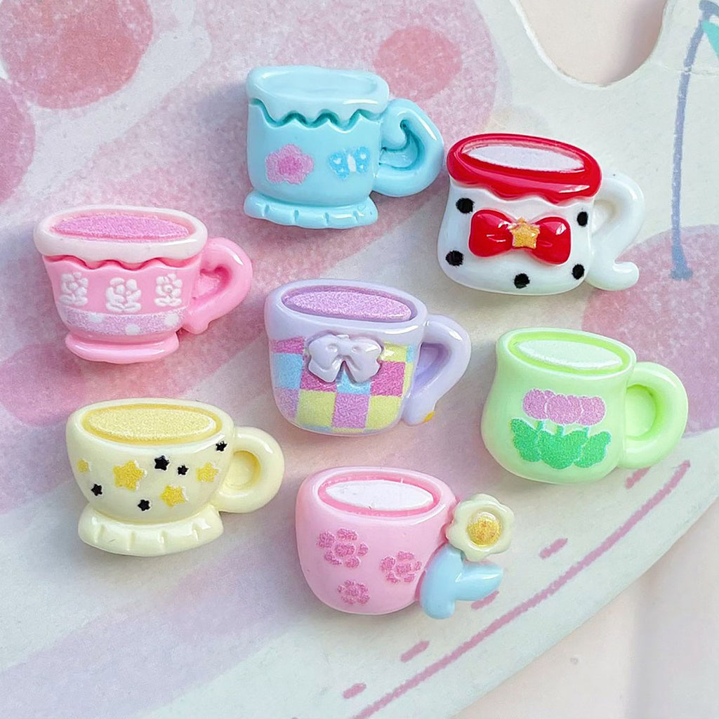 A collection of colorful, whimsical mugs with various designs, including polka dots, flowers, and stars, arranged on a pink and white background.