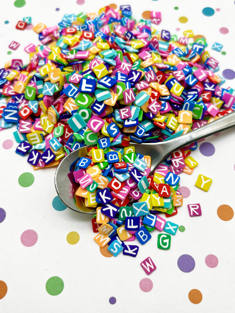 a spoon full of colorful letters sitting on top of a table