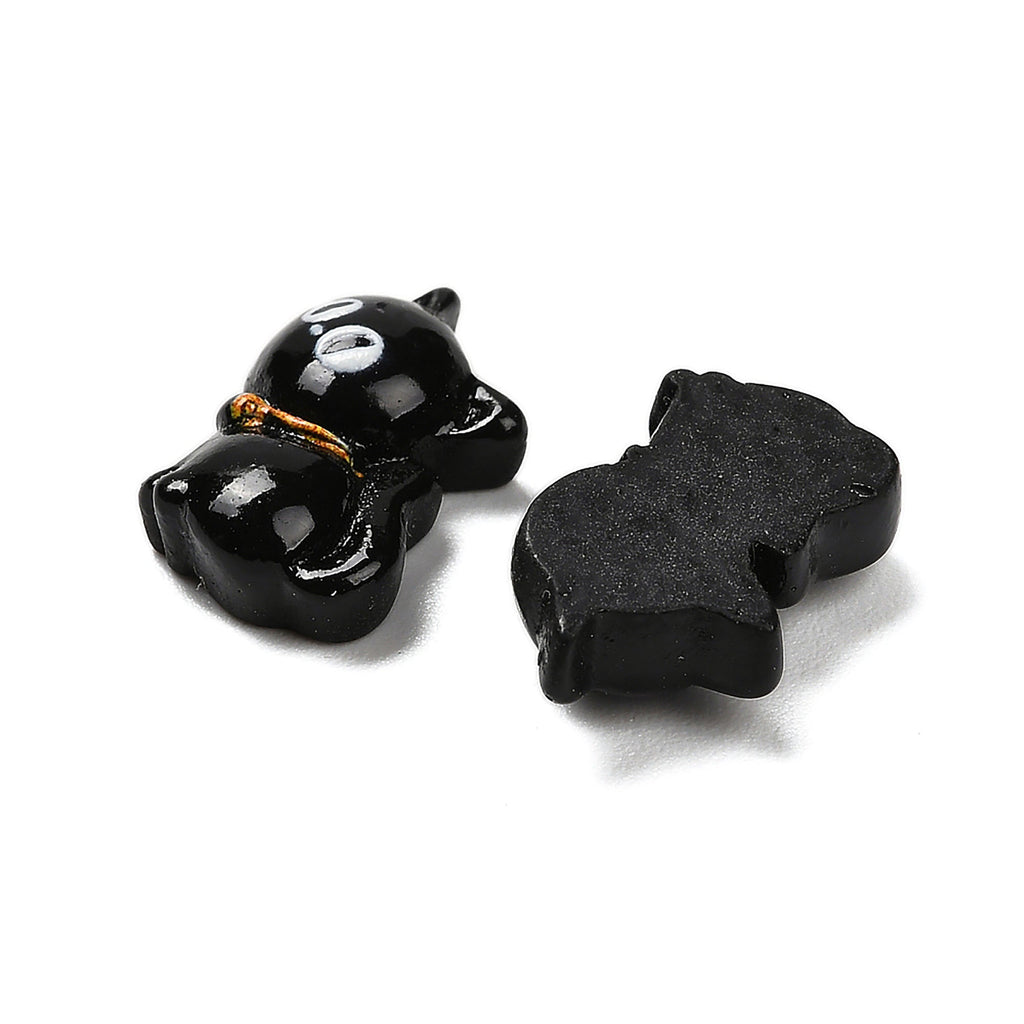 two black cat-shaped objects, one with a gold-colored accent and the other without any additional embellishments.