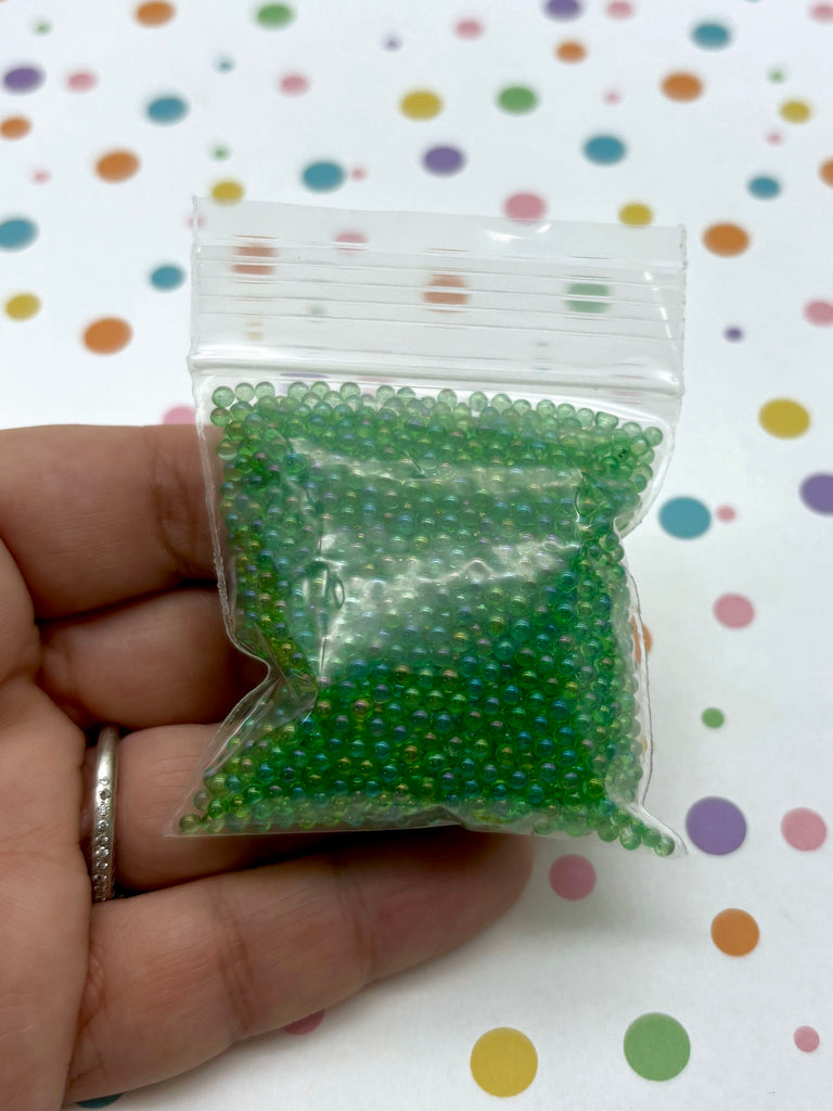 a hand holding a bag of green beads