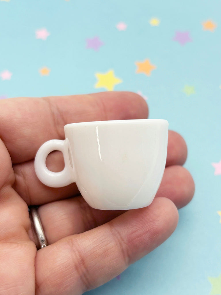 a person holding a tiny coffee cup in their hand