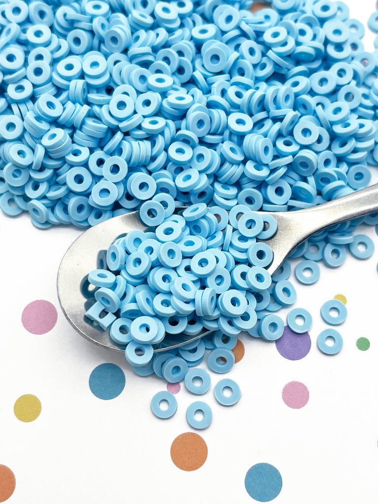 a spoon full of blue beads sitting on top of a table