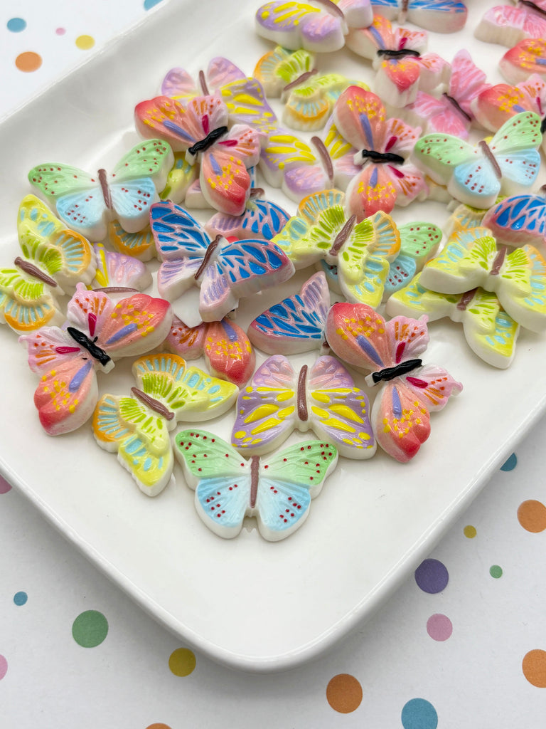 A white plate filled with colorful, patterned, and shaped candies resembling butterflies.