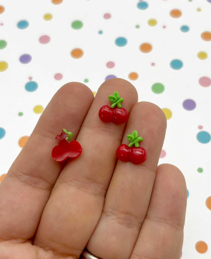 a person holding two tiny cherries in their hand