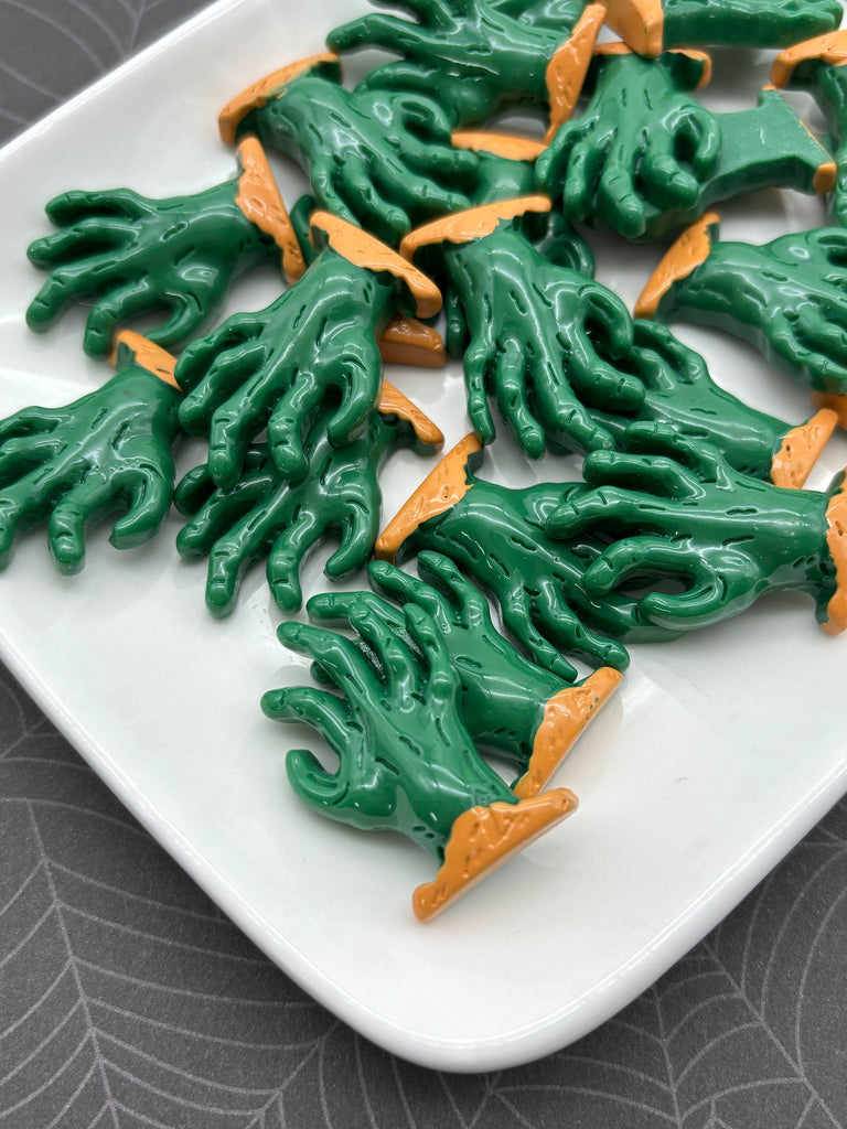 a white plate with a collection of green and orange plastic hands arranged on it.