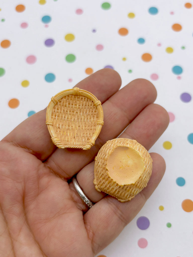 A hand holding two small, light-colored, woven baskets against a background with colorful polka dots.