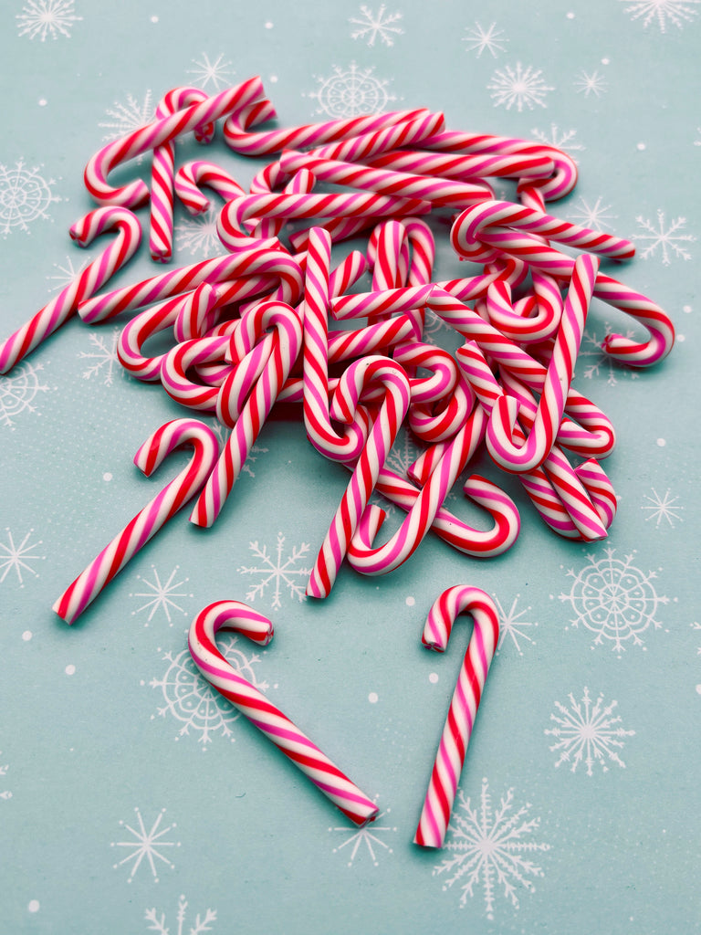a pile of red and white striped candy canes on a blue background with white snowflakes.