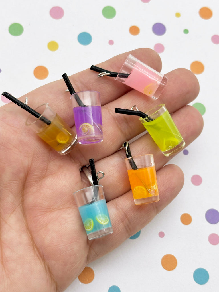 A hand holding a collection of colorful drink glass charms, each containing a straw and a slice of fruit.