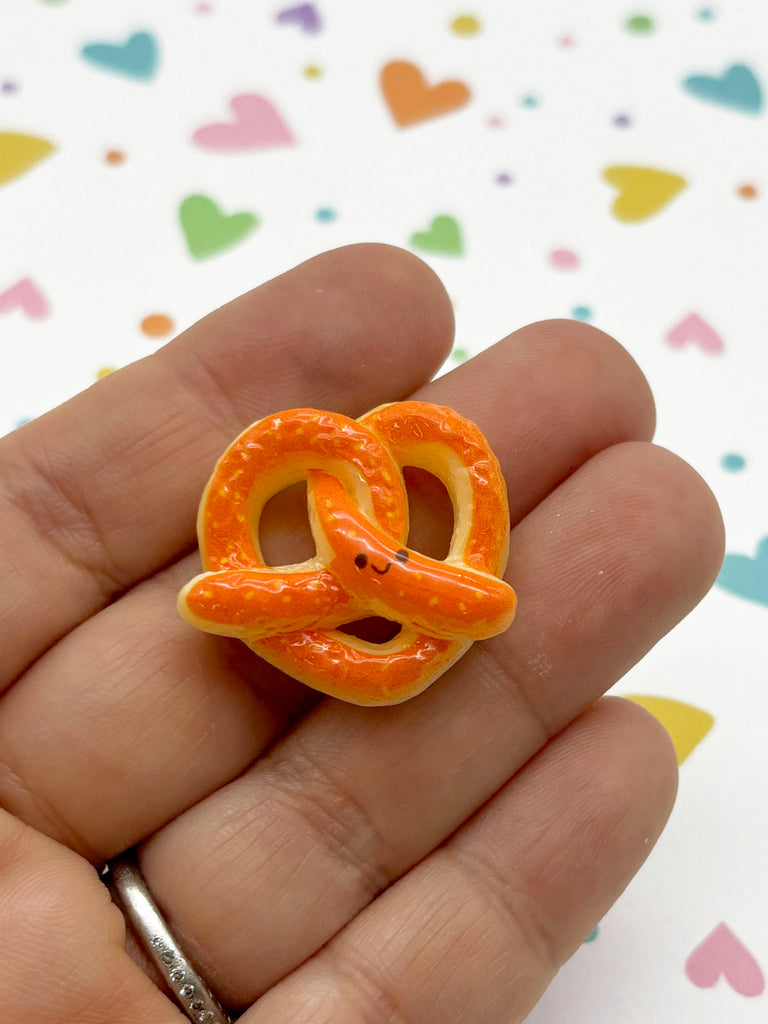 a hand holding a small orange ring in it's palm